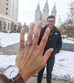 a man standing next to a woman with a ring on her hand in the snow