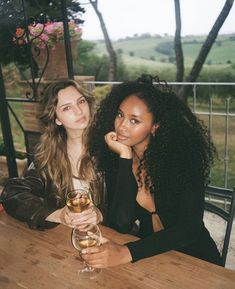 two women sitting at a table with wine glasses