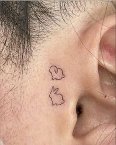 a close up of a person's ear with two small rabbits on the side