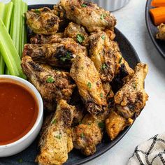 chicken wings and celery sticks on a plate with dipping sauce next to them