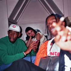 two men and a woman sitting next to each other on a couch with one pointing at the camera