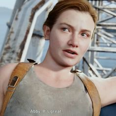 a woman in a tank top holding her arm out and looking at the camera while standing next to a bridge