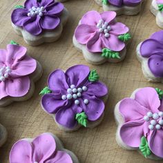 purple and green decorated cookies sitting on top of a wooden table