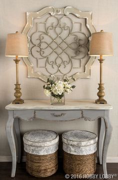 a white table with two baskets underneath it and a mirror on the wall behind it