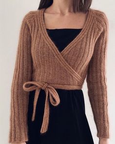 a woman wearing a brown sweater and black dress