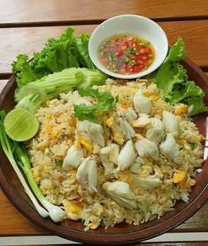 a plate filled with rice, meat and veggies on top of a wooden table