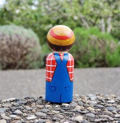 a small toy is sitting on the ground near some rocks and gravel with trees in the background