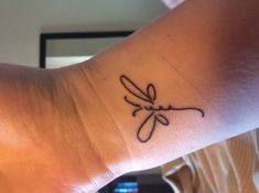 a woman's wrist tattoo with a dragonfly drawn on the side of her arm