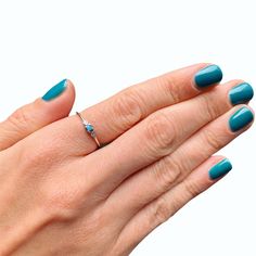 a woman's hand with blue manicured nails and a ring on her finger