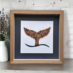 a framed photo of a bird made out of pebbles and sea glass in a wooden frame