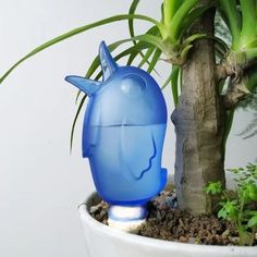 a blue plastic object sitting on top of a potted plant next to a tree