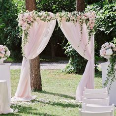 an outdoor wedding setup with pink drapes and flowers