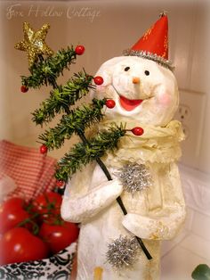 a snowman is holding a christmas tree