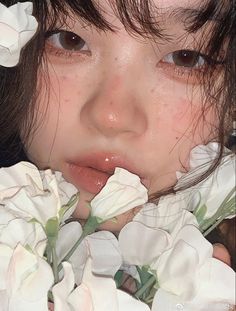 a close up of a child with flowers in her hair and face, looking at the camera