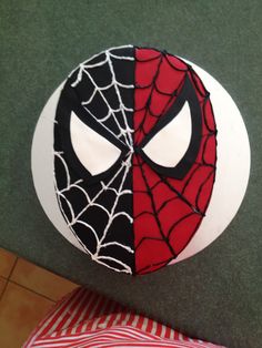 a spiderman cake on top of a table next to a red and black striped pillow