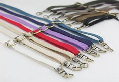 several different colored lanyards are lined up on a white surface with metal hooks