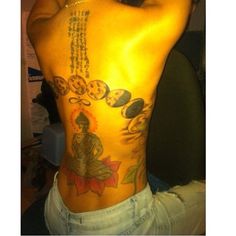 the back of a man with tattoos on his body and an image of a buddha