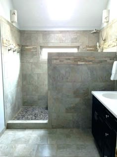 a bathroom with a walk in shower next to a white sink and black cabinetry