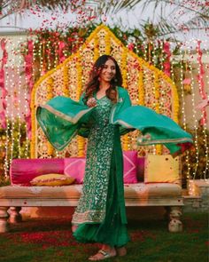 a woman in a green dress is posing for the camera with her arms spread out