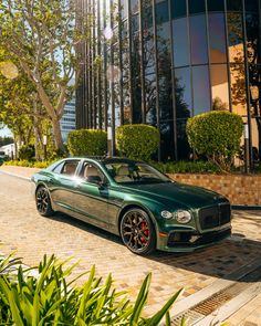 a green car parked in front of a tall building