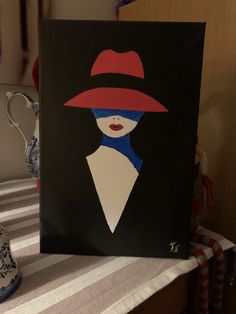 a painting of a woman in a red hat on a table next to a blue and white vase