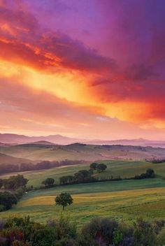 the sun is setting over rolling hills and fields