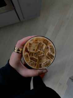 a person holding a drink with ice cubes in it