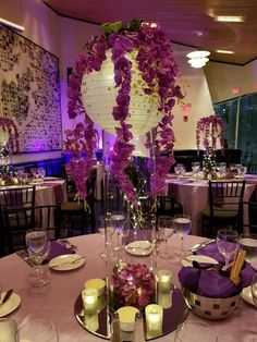 the centerpieces are decorated with purple flowers and lit candles for an elegant touch