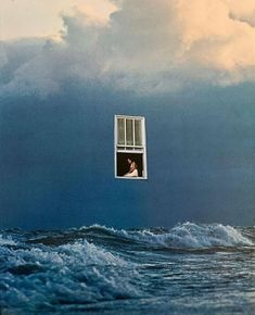 an image of a man looking out the window at the ocean with storm clouds in the background