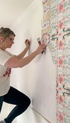 a woman is painting the wall with rollers and paintbrushes in her home