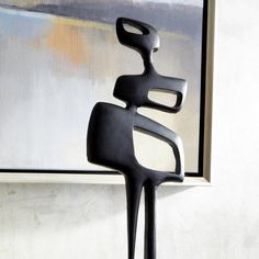 a black sculpture sitting in front of a painting