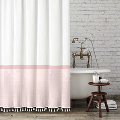 a bath tub sitting next to a shower curtain with pink and white stripes on it