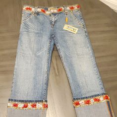 a pair of blue jeans with flowers on the side and an orange flower embroidered on the back