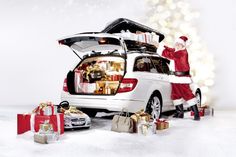 a man dressed as santa claus standing next to a car with presents