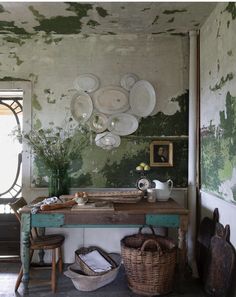 an old table with baskets and plates hanging from it's wall in a room