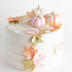 a white cake topped with frosting and gold leaf decorations on top of a table