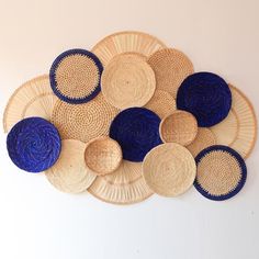 several woven baskets arranged on top of each other in blue and tan colors, against a white wall