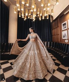 a woman in a gold and silver lehenga standing on a checkered floor