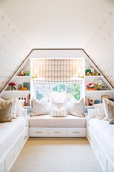 a room with two white couches and some bookshelves on the wall above them