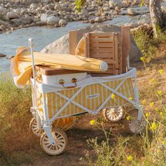 a yellow and white wagon sitting on top of a grass covered field next to a river