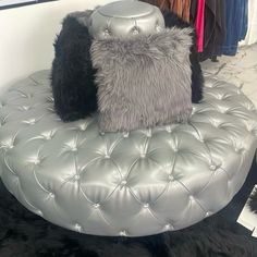 two pillows sitting on top of a leather bench in a clothing store, one is grey and the other is black