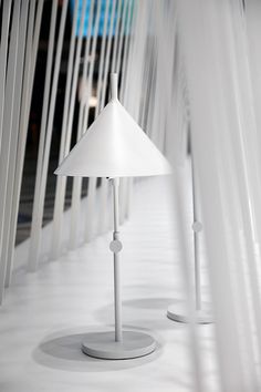 two white lamps sitting next to each other on top of a floor covered in lines