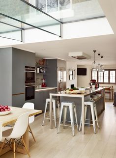 an open kitchen and dining room with skylights in the ceiling is very modern looking