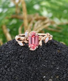 a pink tourmaline ring sitting on top of a rock