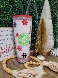 a starbucks cup sitting on top of a wooden table next to a christmas tree and other decorations