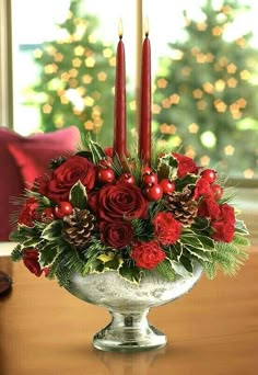 a christmas centerpiece with red roses and pine cones in a silver bowl on a table