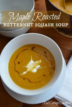 a white bowl filled with butternut squash soup on top of a wooden table next to other bowls