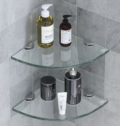 two glass shelves in the corner of a bathroom with soap, lotion and hand sanitizers