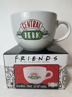 a coffee cup sitting on top of a box with its lid open and the words central perk in front of it