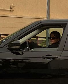 a woman sitting in the driver's seat of a black car